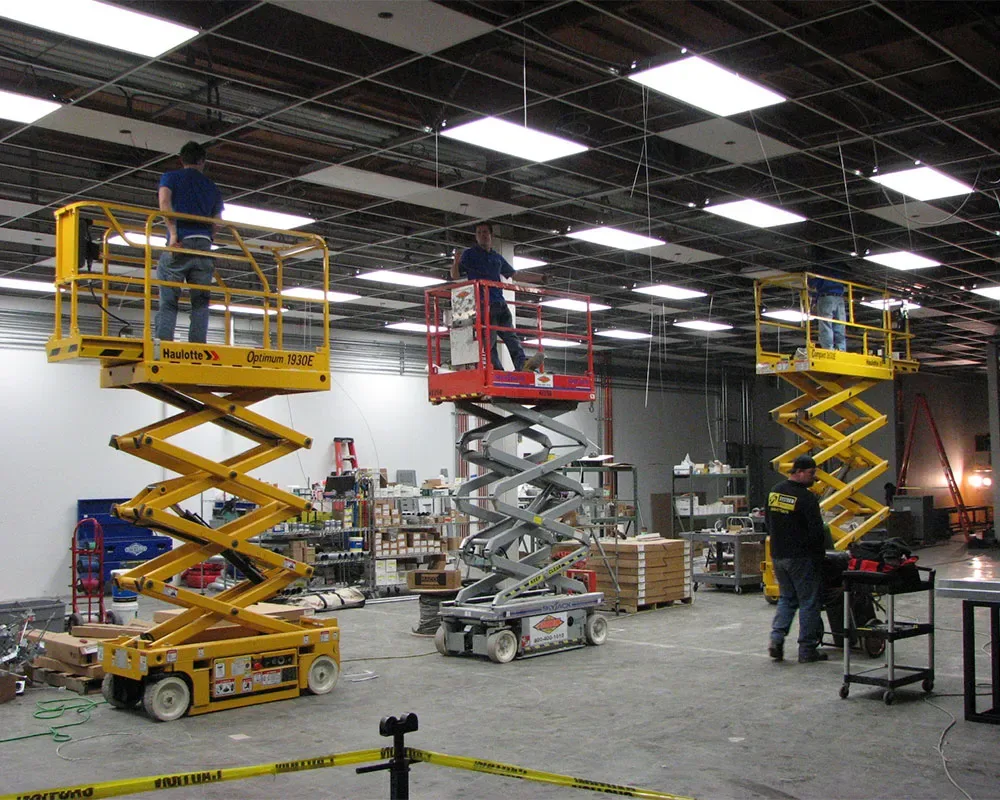 Commercial electrical crew on lifts installing overhead lighting